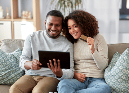 A couple sits on their couch and online shops.