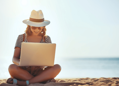 A woman sitting on the beach with her laptop