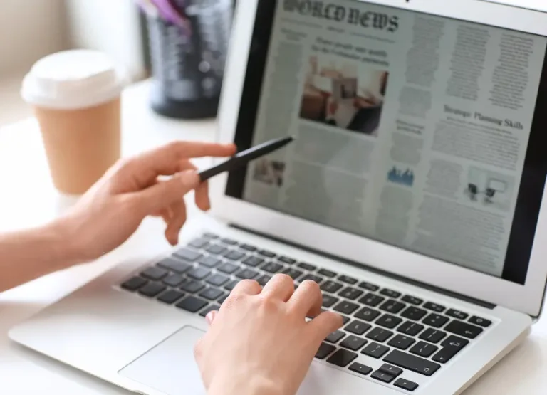 A person reads a newspaper on their laptop