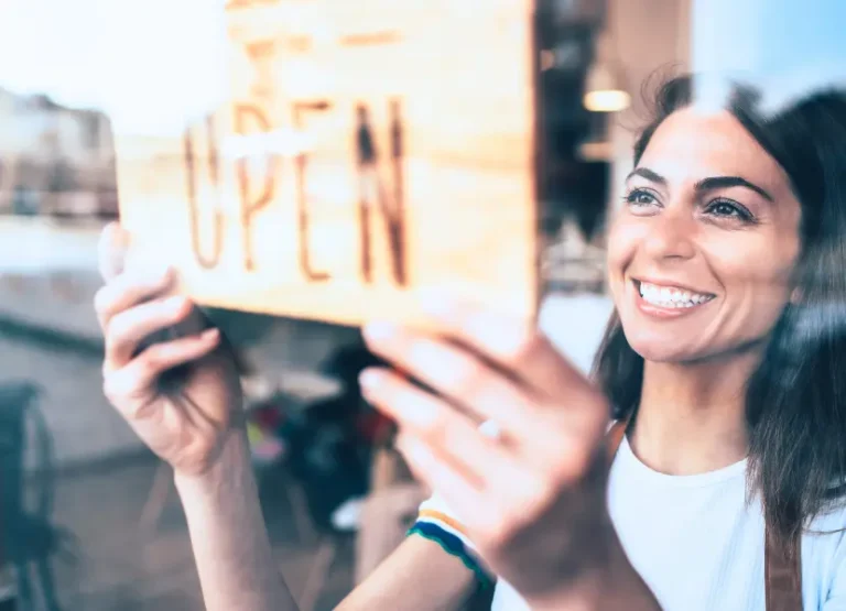 A shop owner hangs an "open" sign onto the shop door.