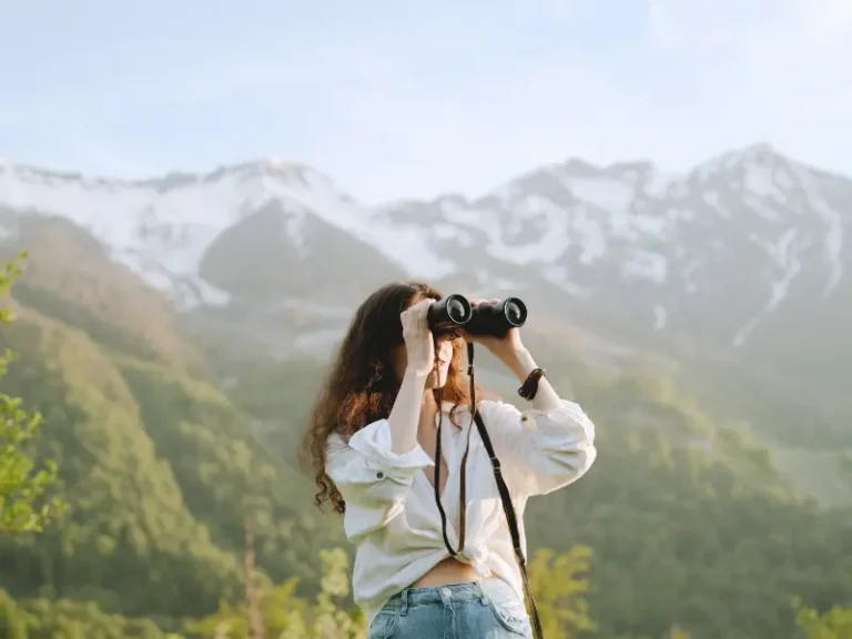 A woman looks into the distance with binoculars.