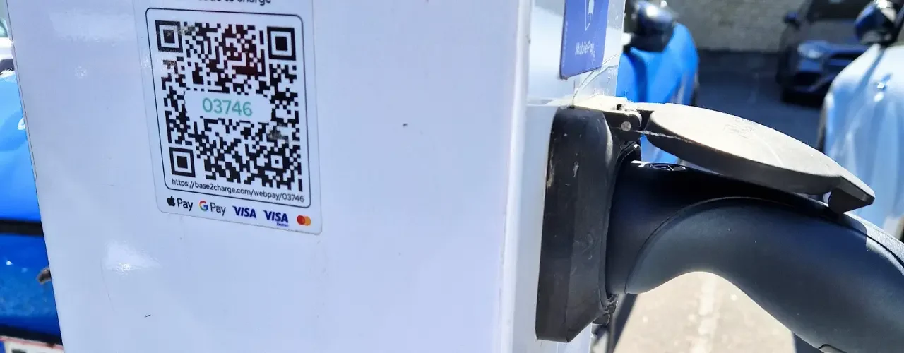 A Base2Charge charging station with a QR cod and different payment options displayed.
